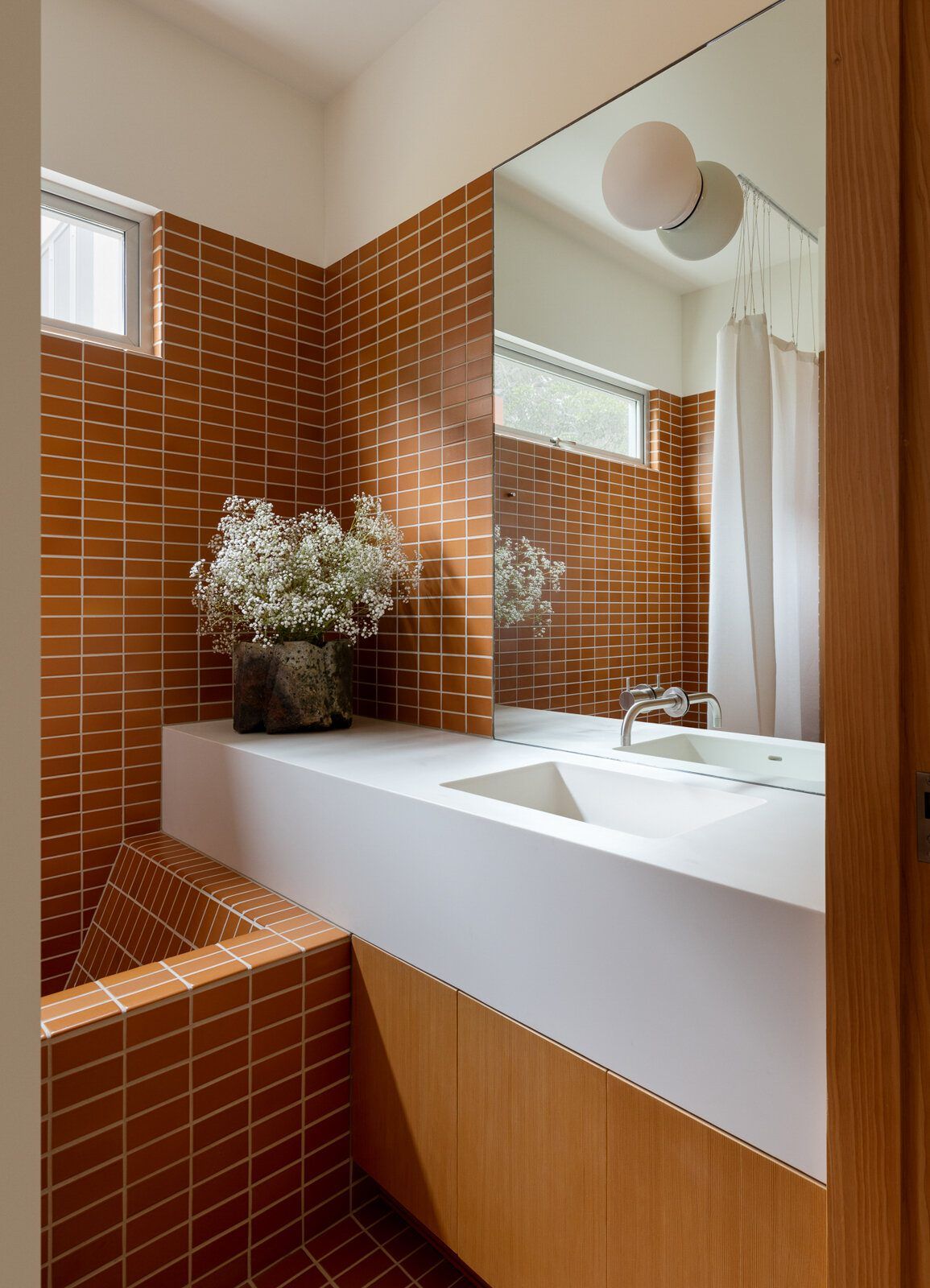 Altair: Bathroom with rust-glazed tile, a white integrated sink and round mirror