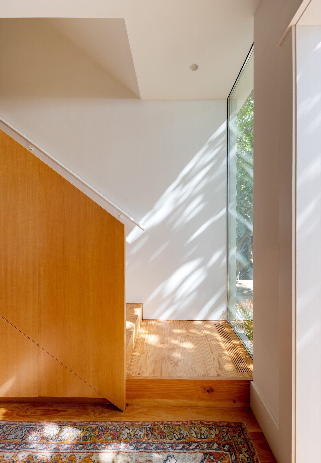 Altair: Fir-paneled stair landing lit by a tall slot window