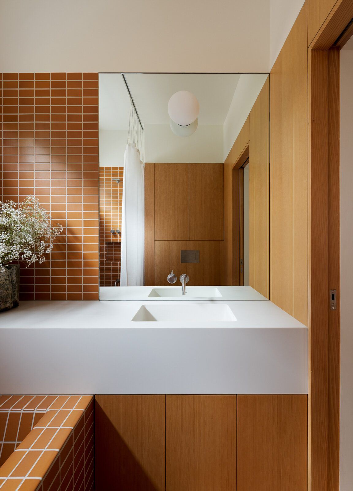 Altair: Bath vanity with rust tile, a mirrored cabinet and globe sconce
