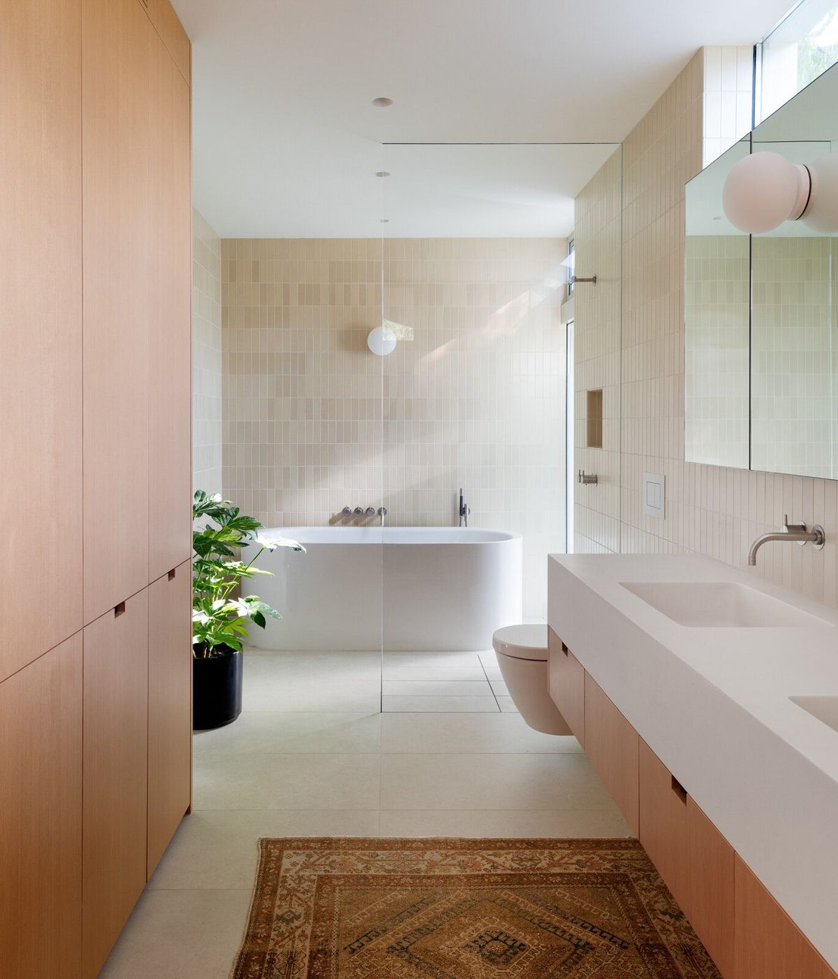 Altair: Primary bath with fir cabinetry, a long stone vanity and freestanding tub beyond