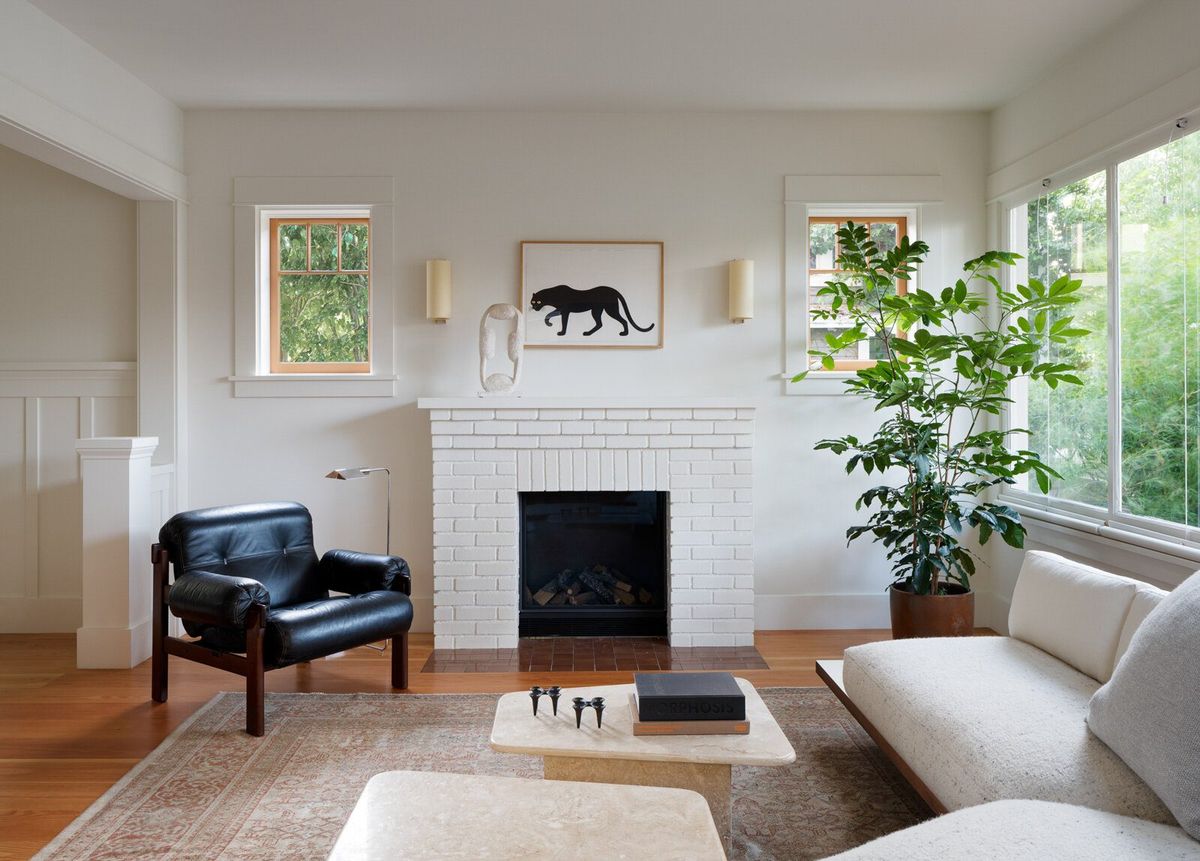 Altair: Living room with a white brick fireplace, black leather chair and low sofa