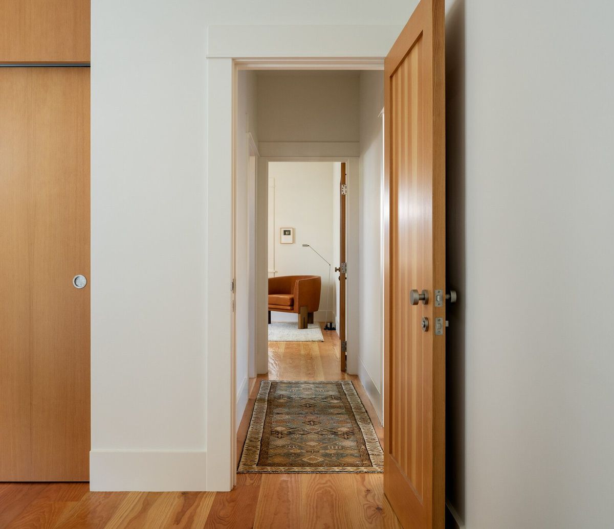 Altair: Hallway through fir doors to a bedroom with a rug runner