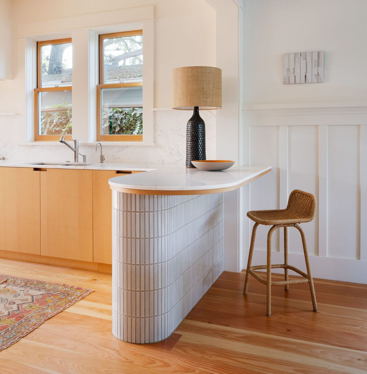 Altair: Kitchen peninsula with a curved white tile base and fir counter stools