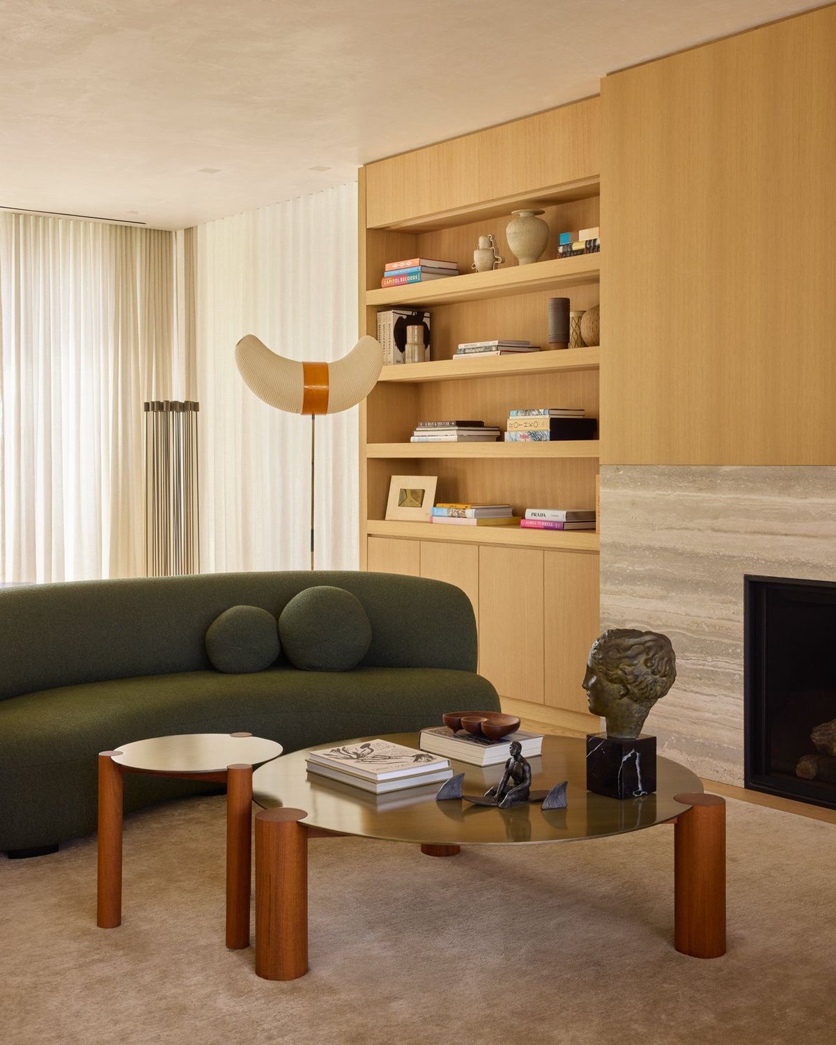 Ashcroft: Sitting area with a curved green sofa beside an oak bookcase and fireplace