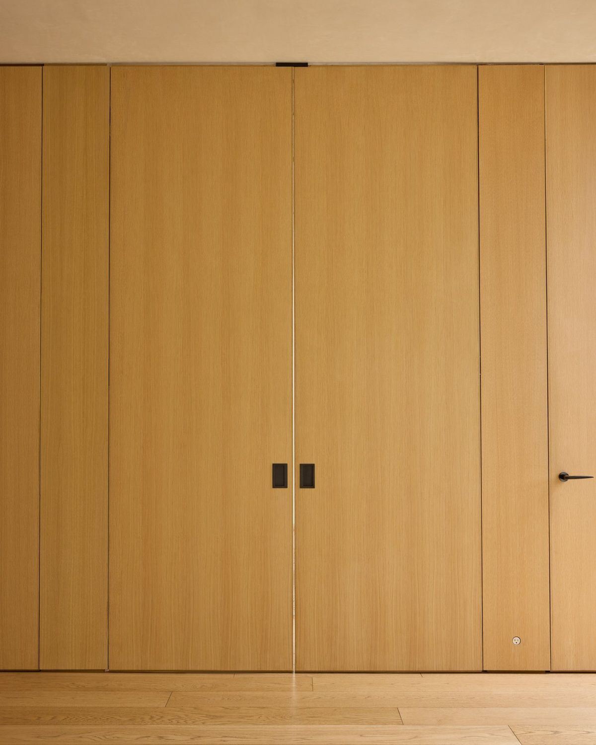 Ashcroft: Floor-to-ceiling flush oak cabinetry with black pulls
