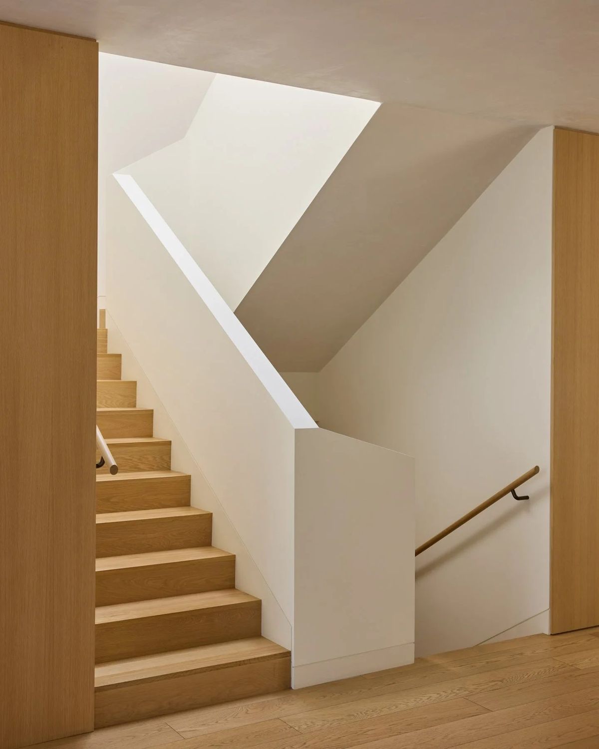 Ashcroft: Oak stair rising along white walls with a wall-mounted handrail