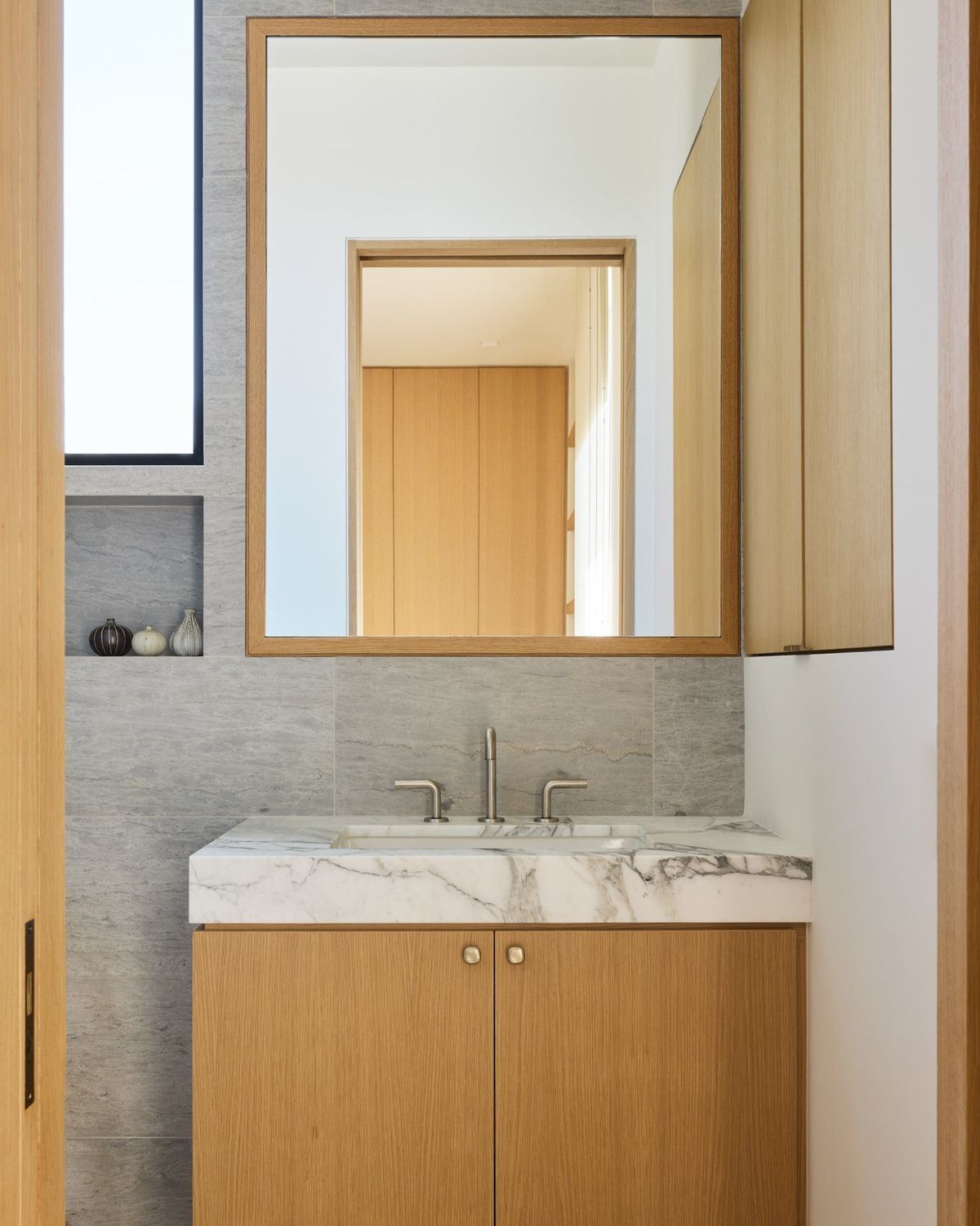 Ashcroft: Powder room with a marble-topped oak vanity and wood-framed mirror