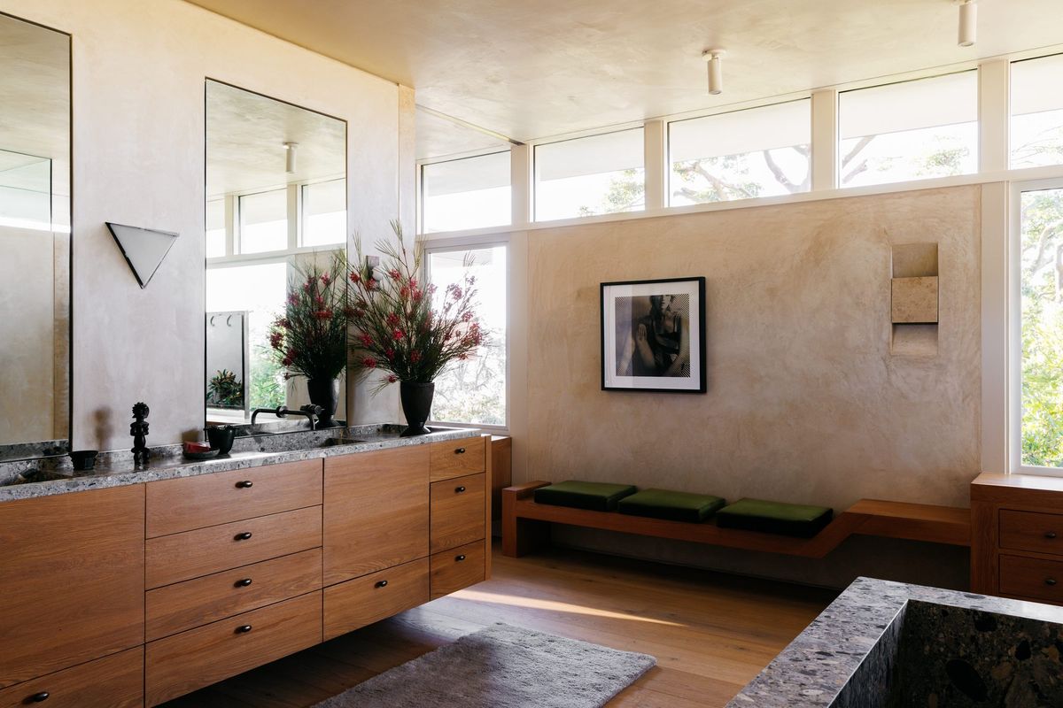 Carla Ridge: Primary bath with a wood vanity, plaster walls and clerestory windows