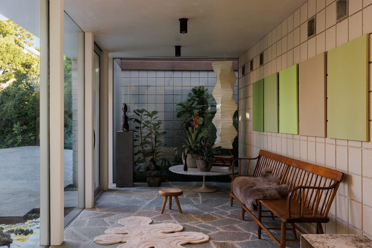 Carla Ridge: Stone-floored sunroom with a spindle bench, green panels and indoor plants