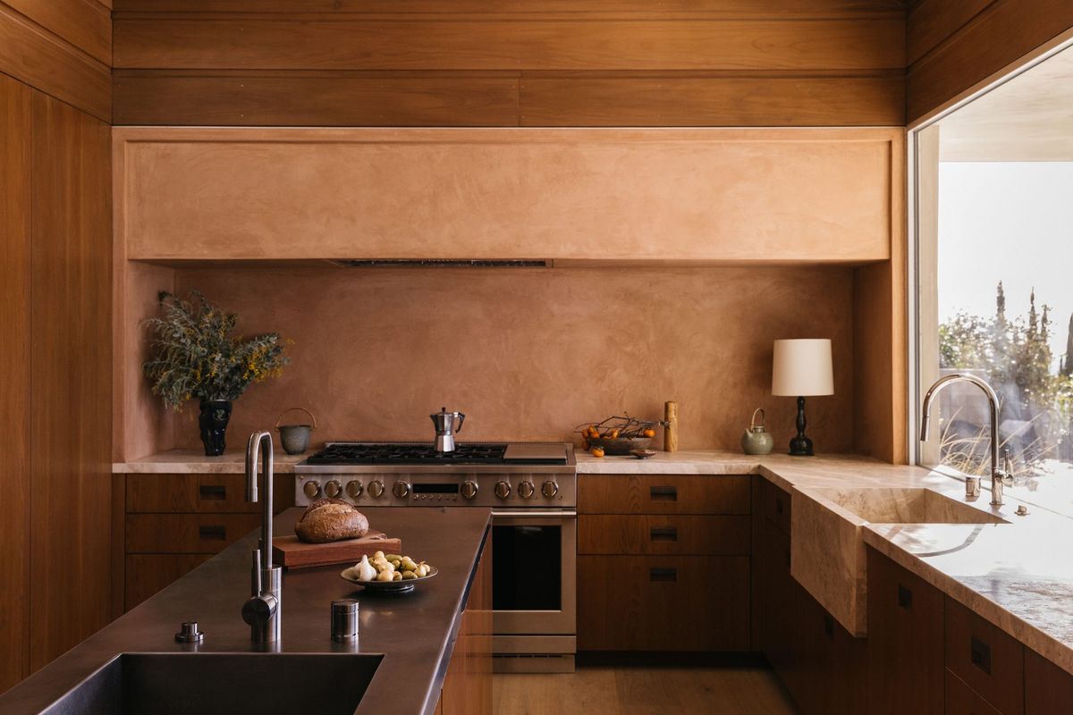 Carla Ridge: Wood-paneled kitchen with a warm clay-plaster wall, range and corner window