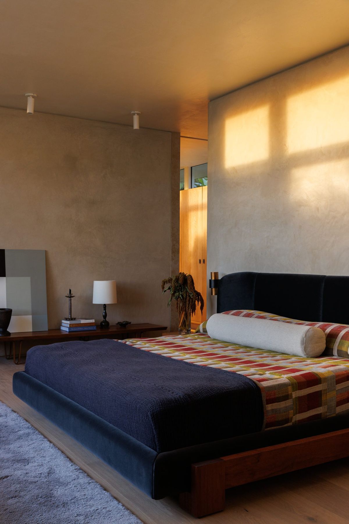 Carla Ridge: Bedroom with a navy platform bed in warm afternoon light