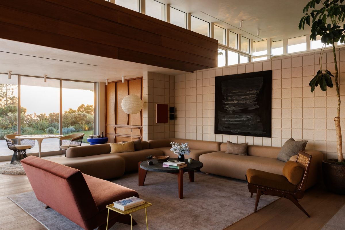 Carla Ridge: Living room with a concrete block wall, sectional sofa and red lounge chairs