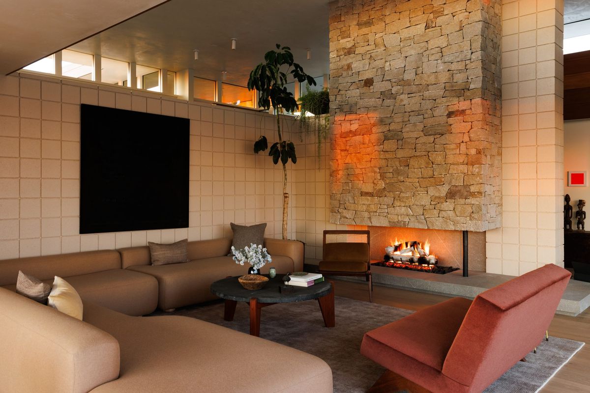 Carla Ridge: Living room with a stacked-stone fireplace, sectional and red lounge chair