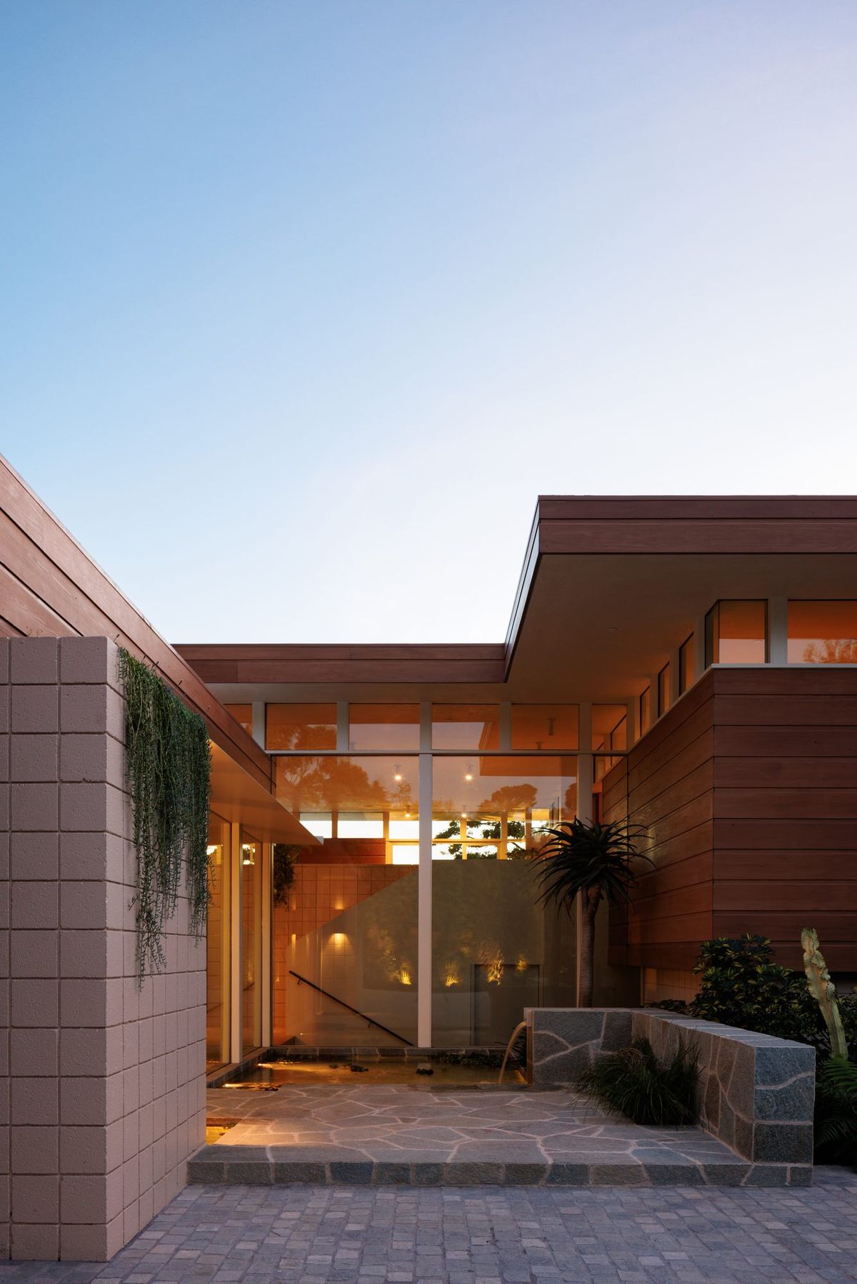 Carla Ridge: Concrete block entry court leading to the glowing front door at dusk