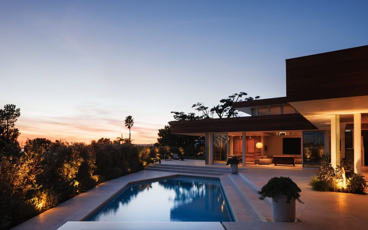 Carla Ridge: Pool and lit living spaces at dusk against the hillside skyline