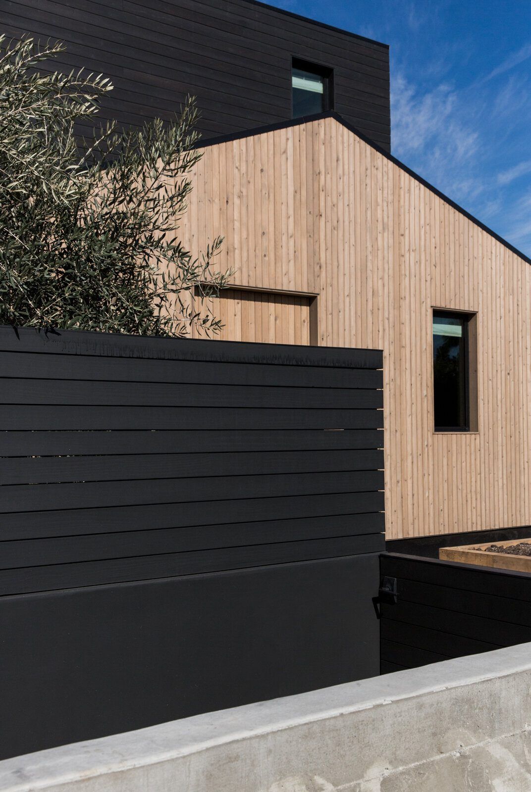 Flower: Wood-clad gable meeting black horizontal-board siding
