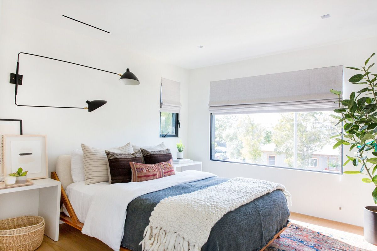 Flower: Bright bedroom with a swing-arm wall lamp and layered bedding