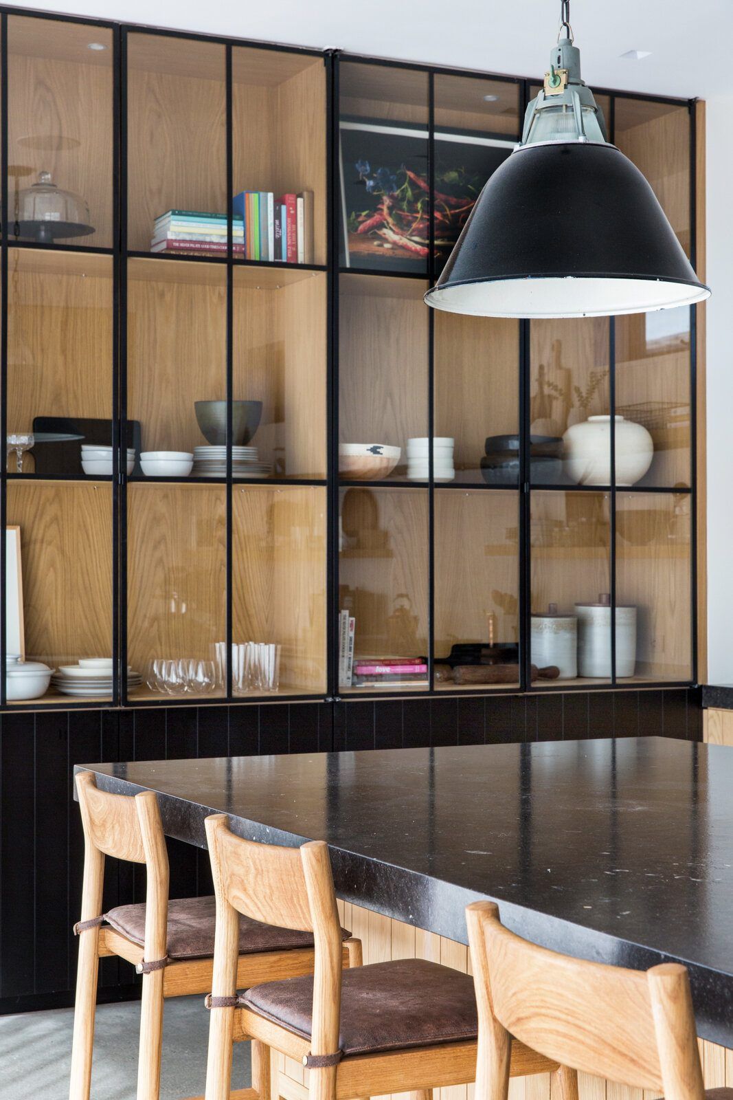 Flower: Oak and black-steel shelving above a dark counter with woven stools