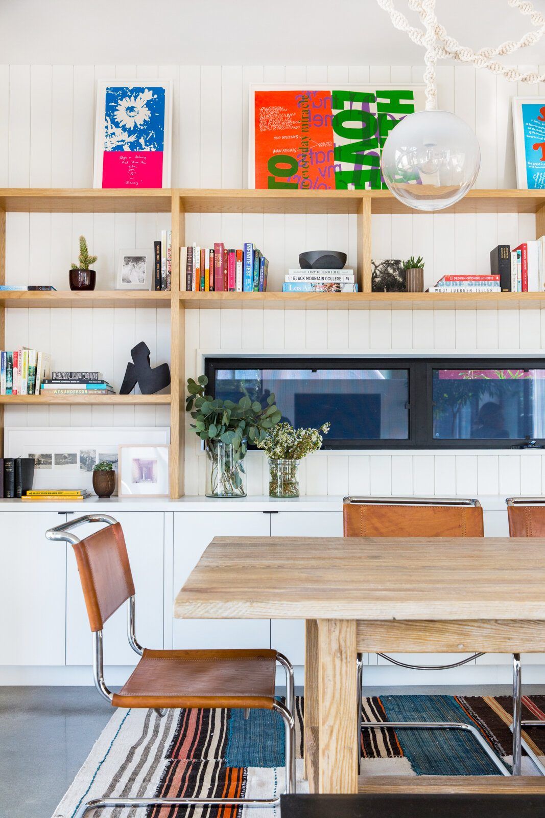 Flower: Dining table beneath colorful built-in bookshelves