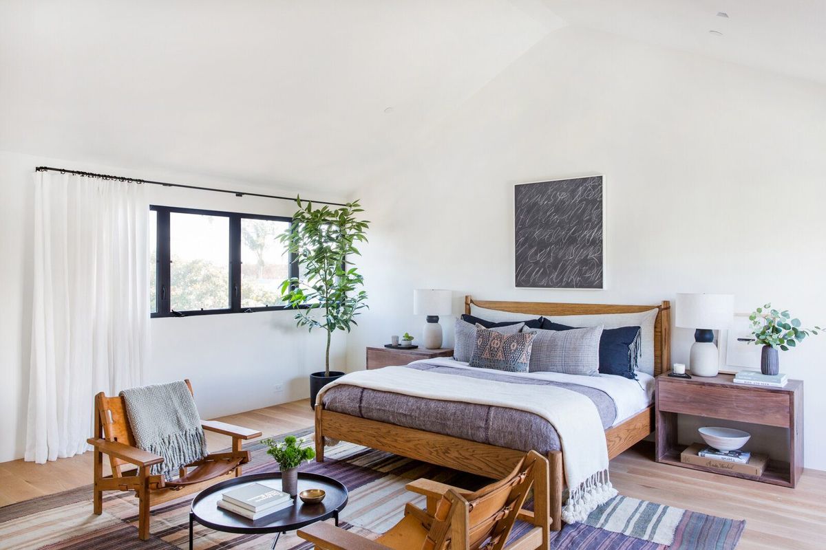 Flower: Primary bedroom with a wood bed frame, leather sling chair and rugs