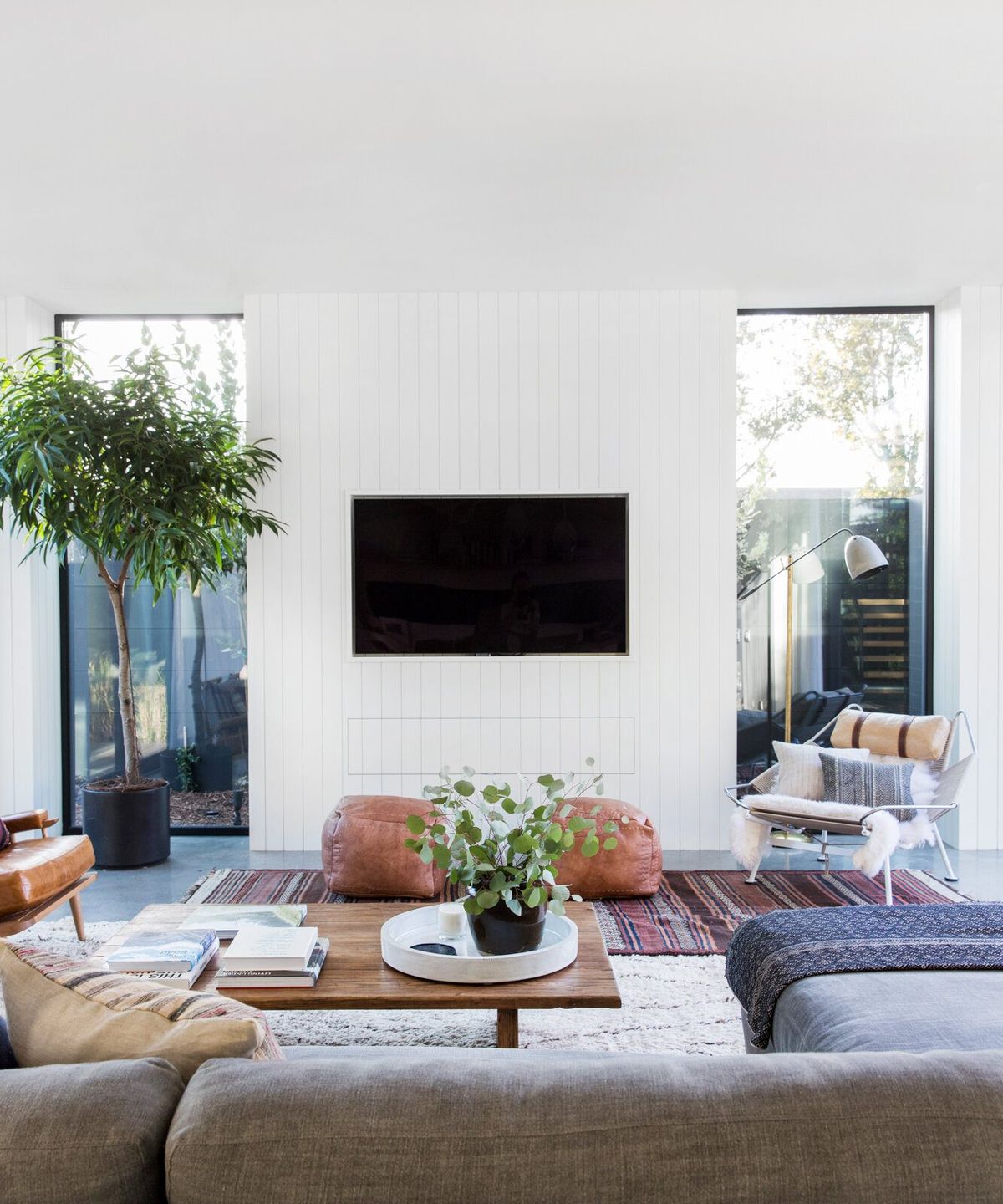 Flower: Family room with a white paneled media wall and leather poufs