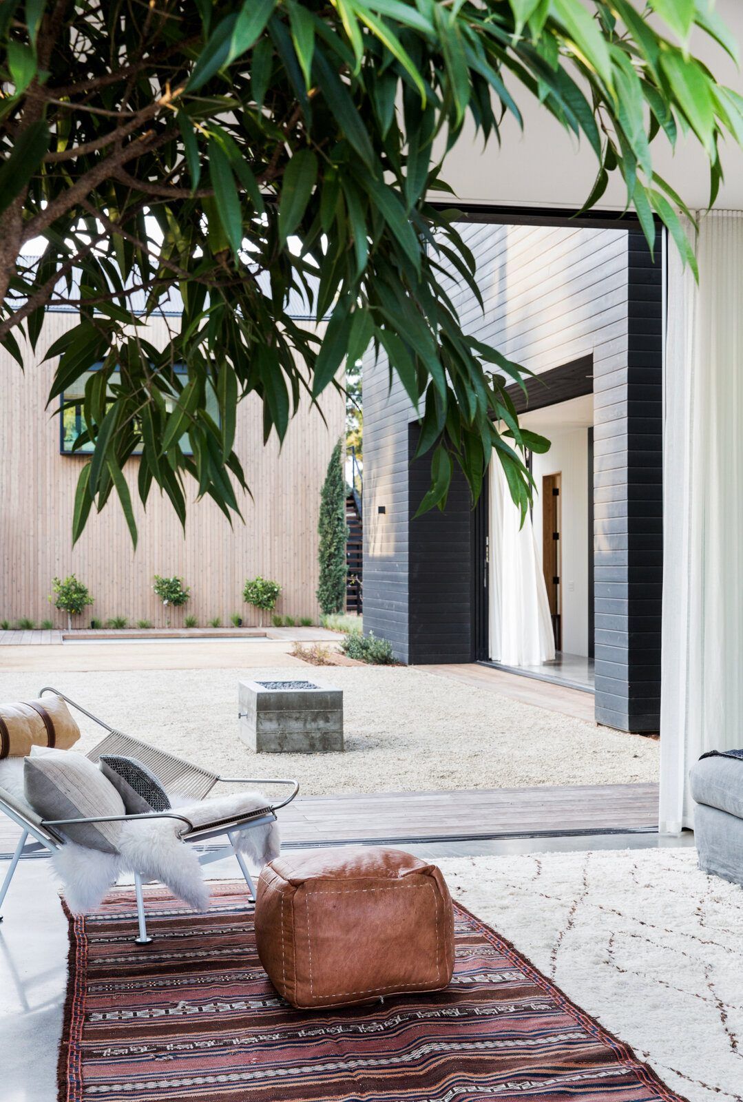 Flower: Patio seen through foliage with leather poufs and a courtyard beyond