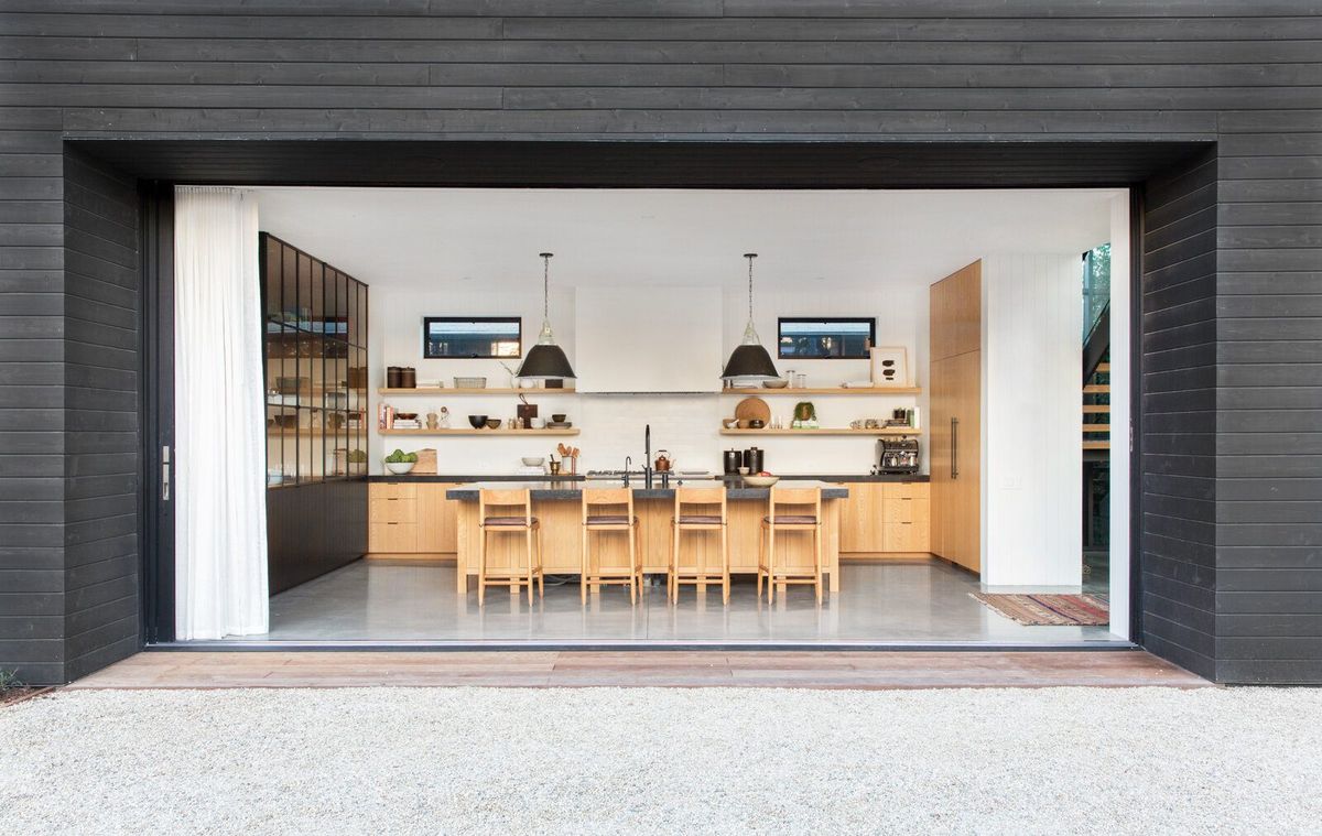 Flower: Kitchen seen through a wide black-clad opening from the courtyard