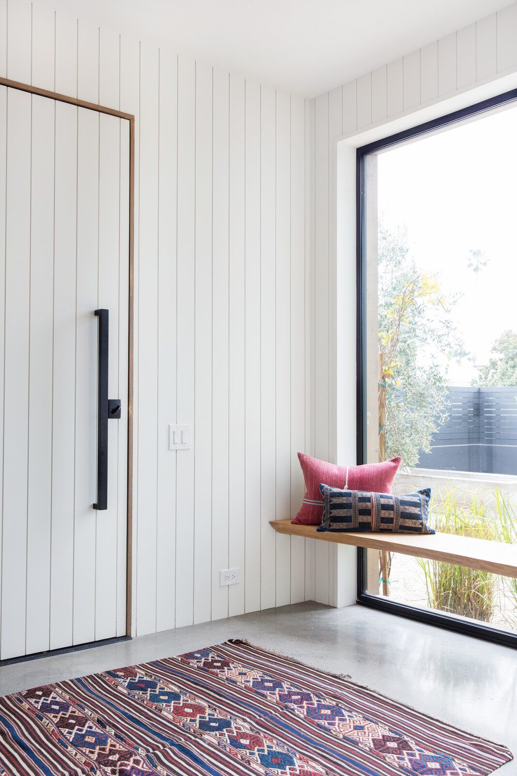 Flower: Entry with a white board-paneled door, window bench and kilim rug