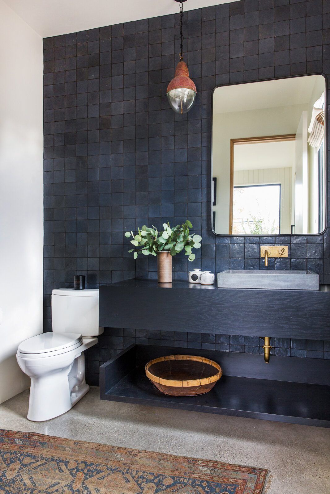 Flower: Powder room with black tile, a floating black vanity and brass mirror