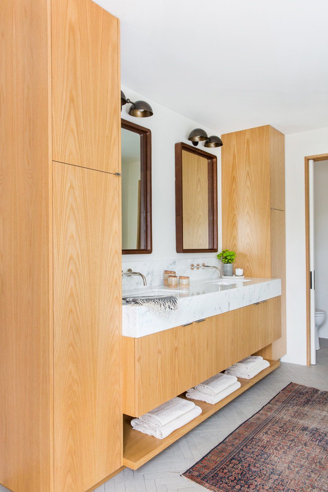 Flower: Oak double vanity with wall-mounted mirrors and a vintage rug