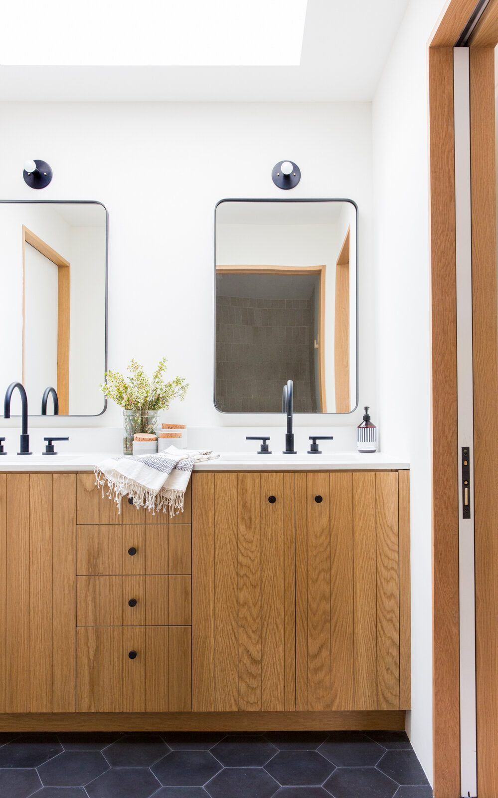 Flower: Oak vanity with round mirrors and black hexagon floor tile