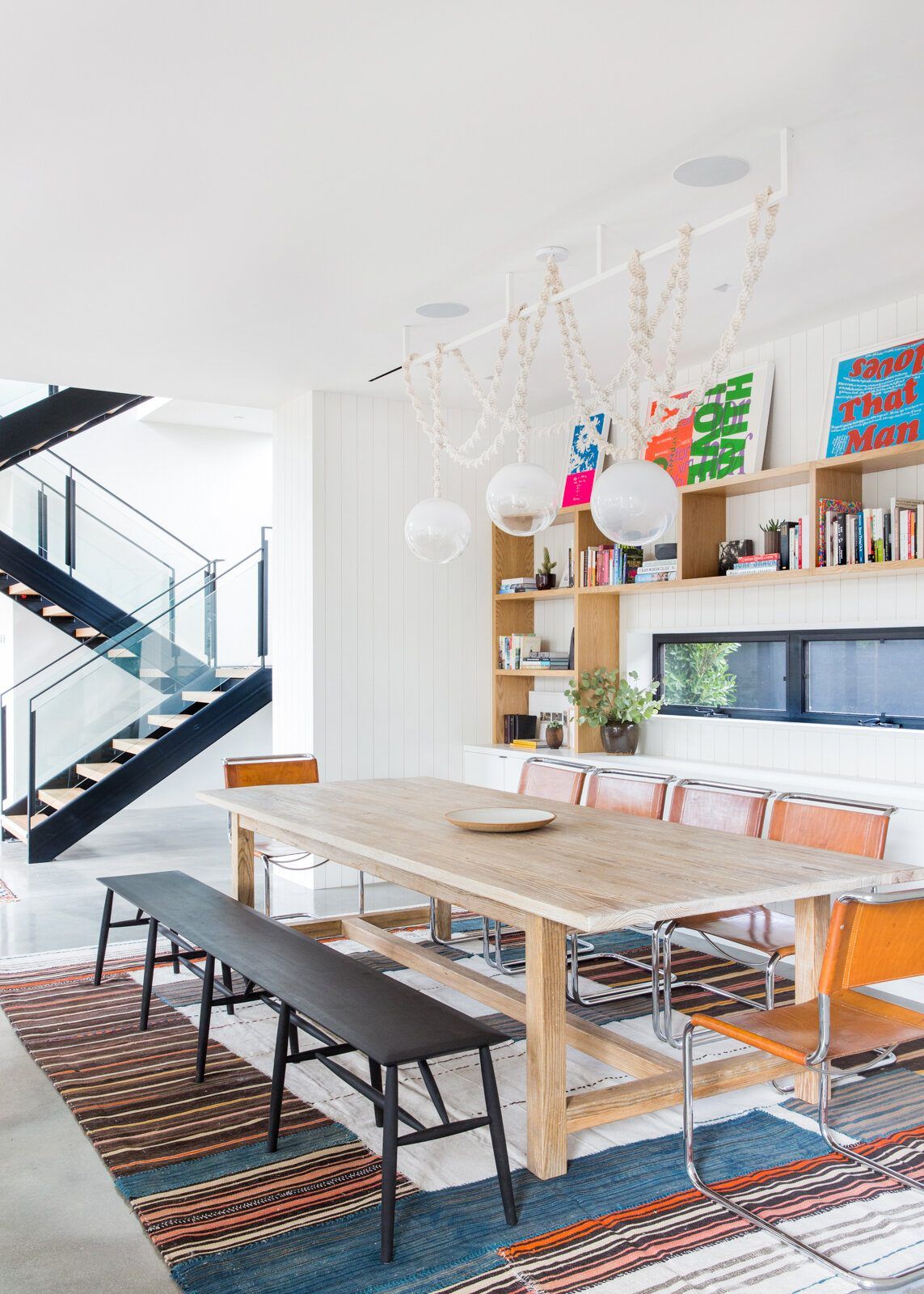 Flower: Dining room with a long wood table, bench, bookshelves and steel stair