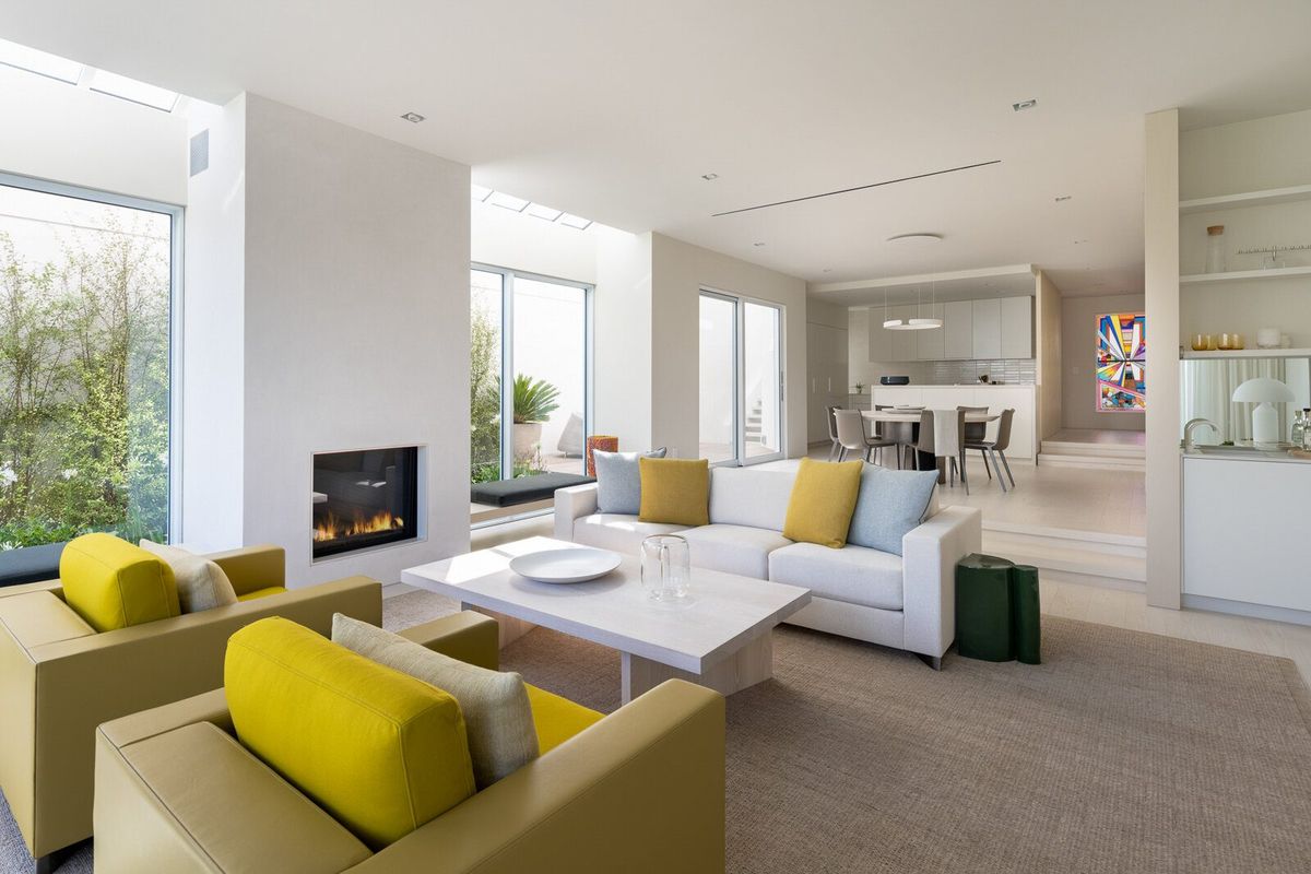 Harbor: Open living room with yellow chairs, fireplace column and kitchen beyond