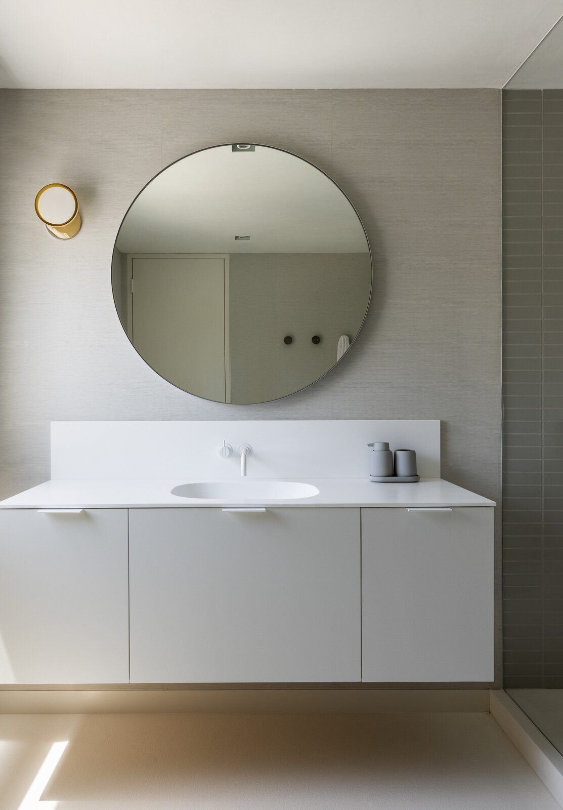 Harbor: White floating vanity with a round mirror and brass sconce
