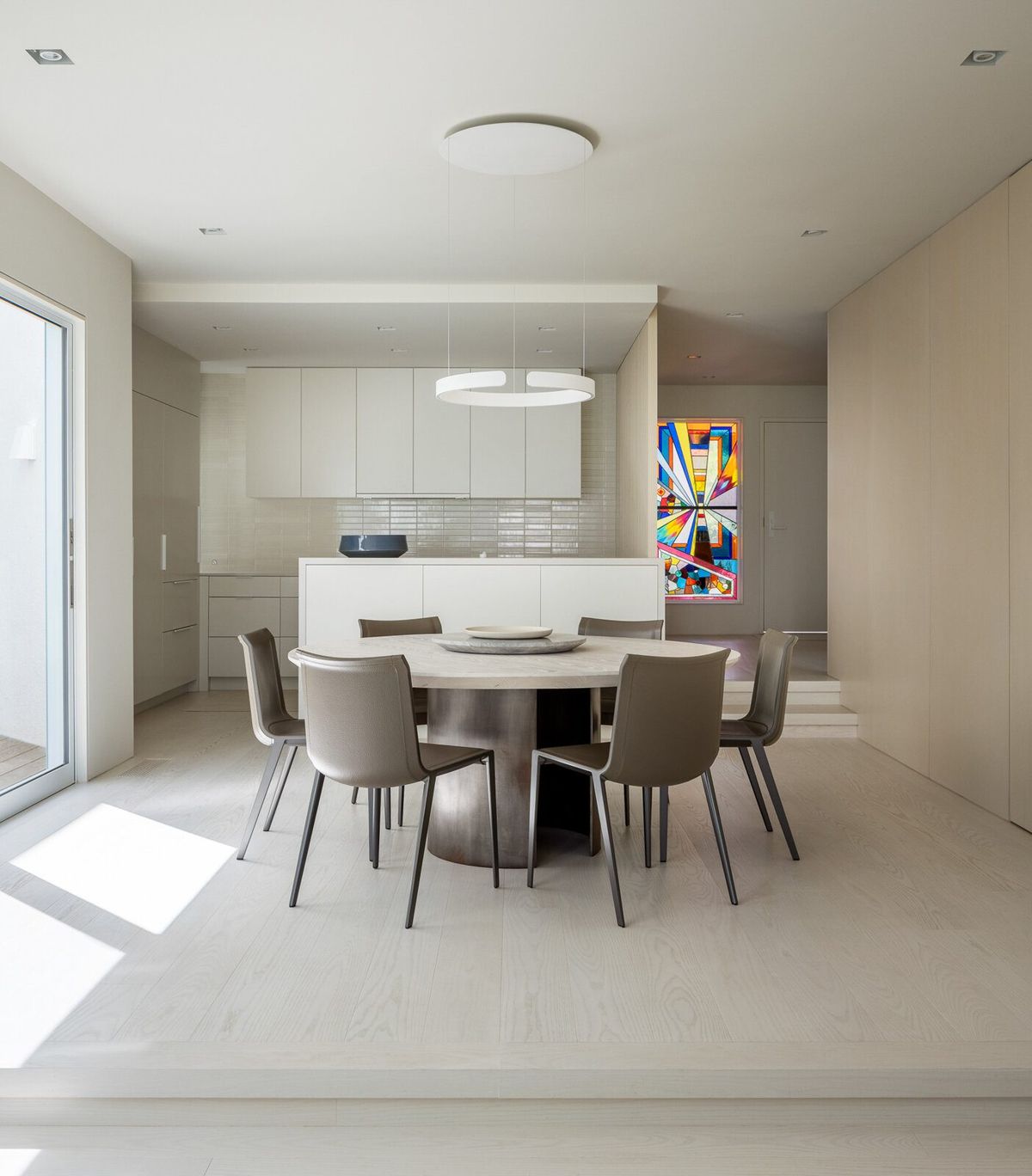 Harbor: Dining area with a round table and white kitchen beyond