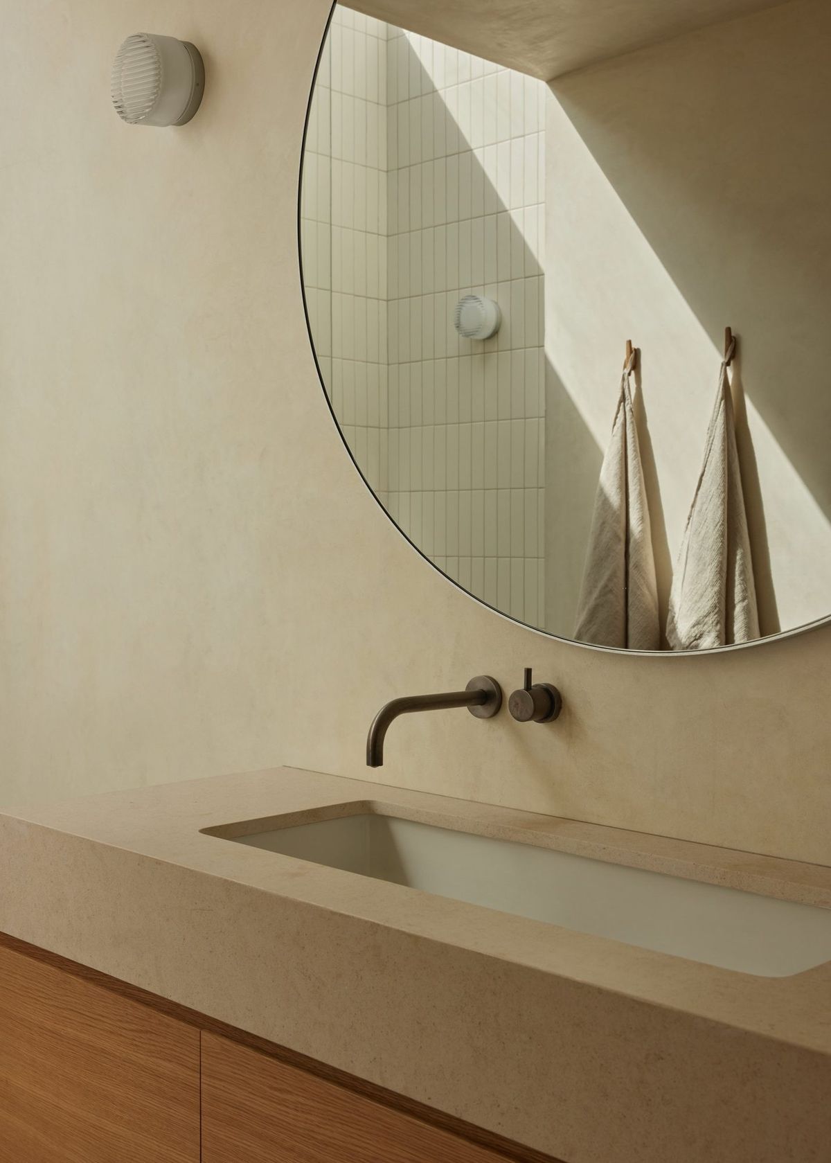 Meier: Plaster sink with a wall-mounted bronze faucet and round mirror