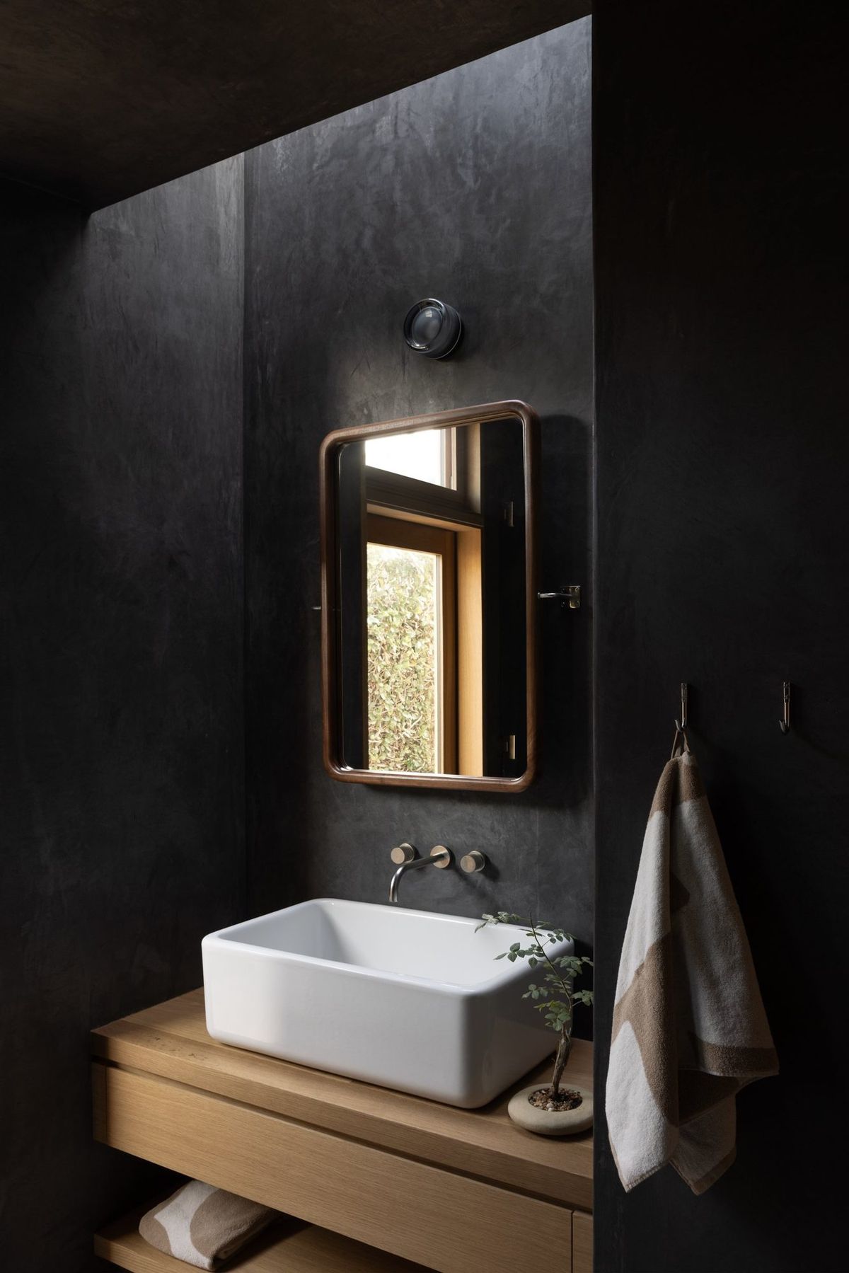 Meier: Powder room with a white vessel sink against dark plaster