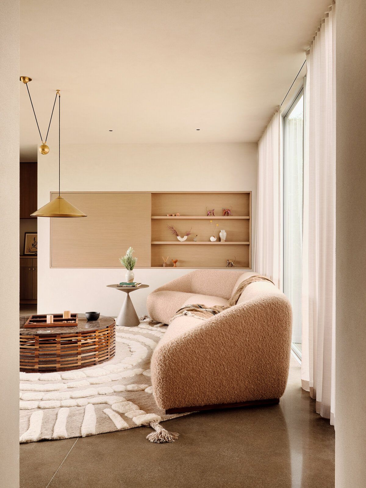 Modjeska: Sitting room with a curved boucle sofa and brass pendant