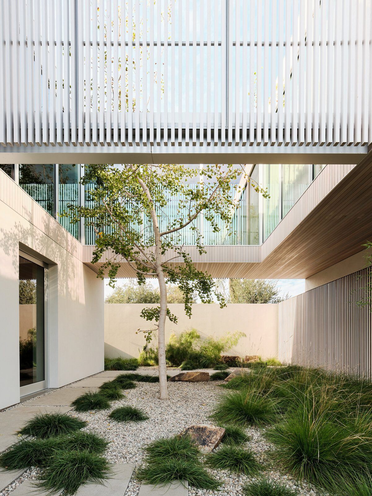 Modjeska: Gravel courtyard and tree seen beneath the upper-floor louvers