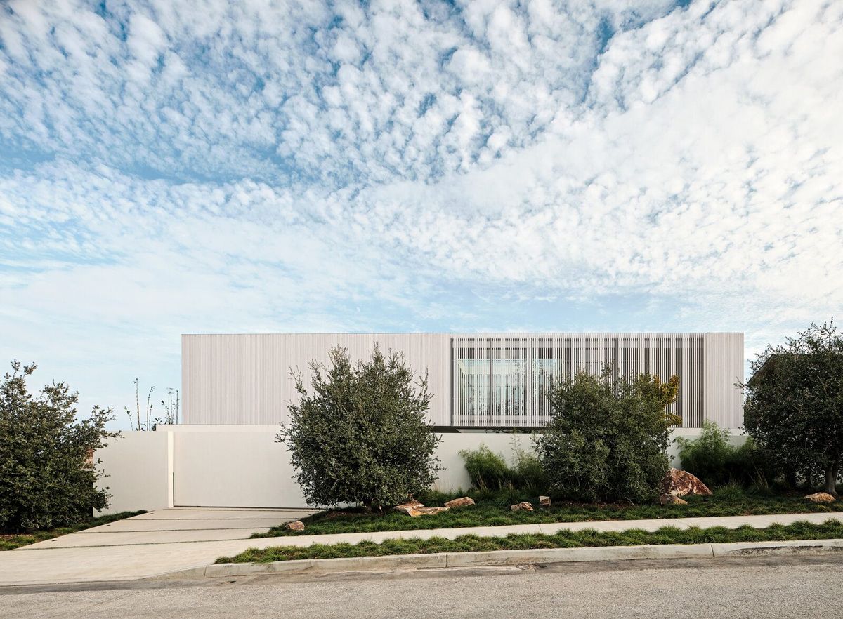 Modjeska: Street view of the low white house under a sky of clouds
