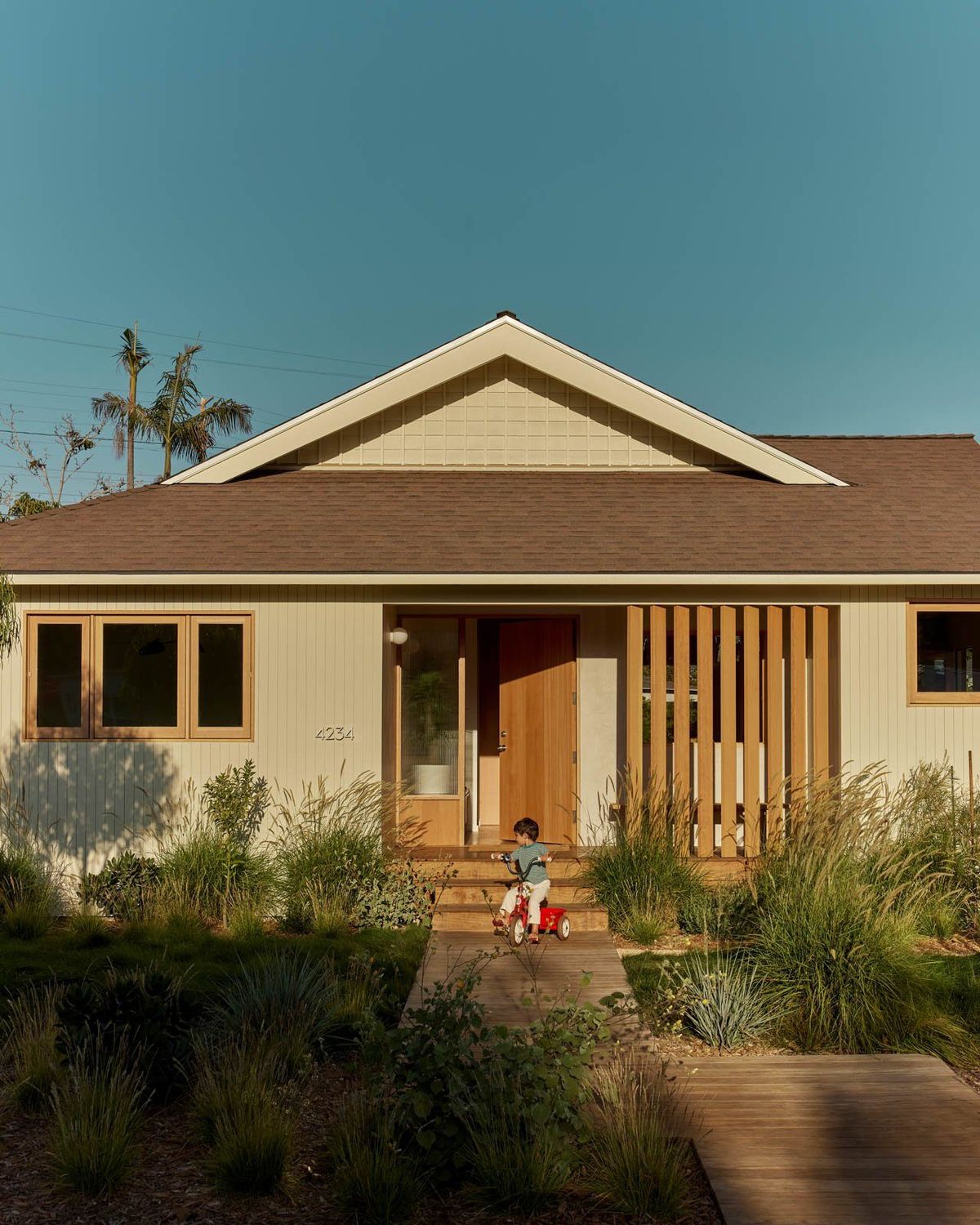 Stewart: Renovated 1950s bungalow with a new gable and wood screen behind a native garden