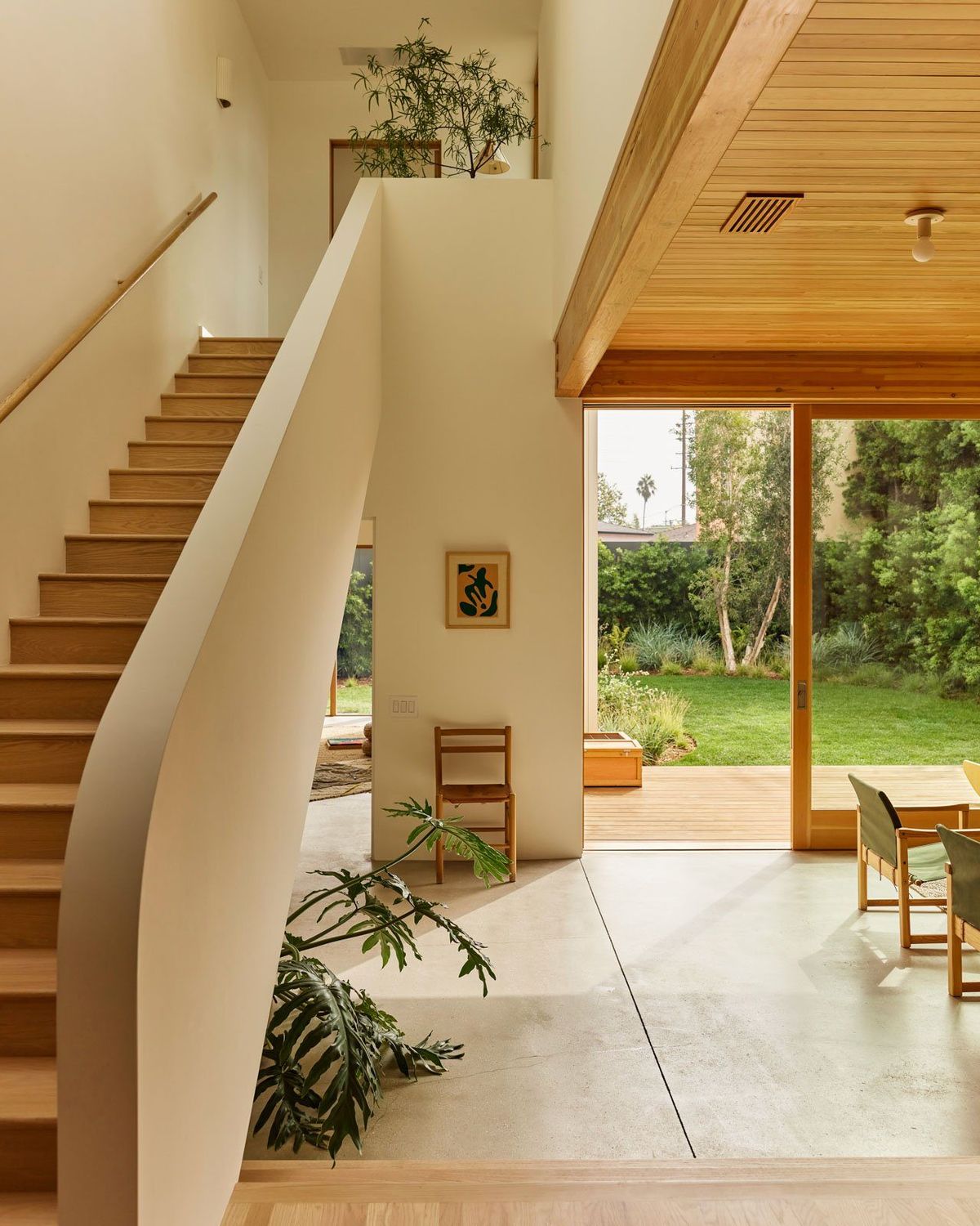 Stewart: Sculptural white staircase with a wood handrail and a view to the garden