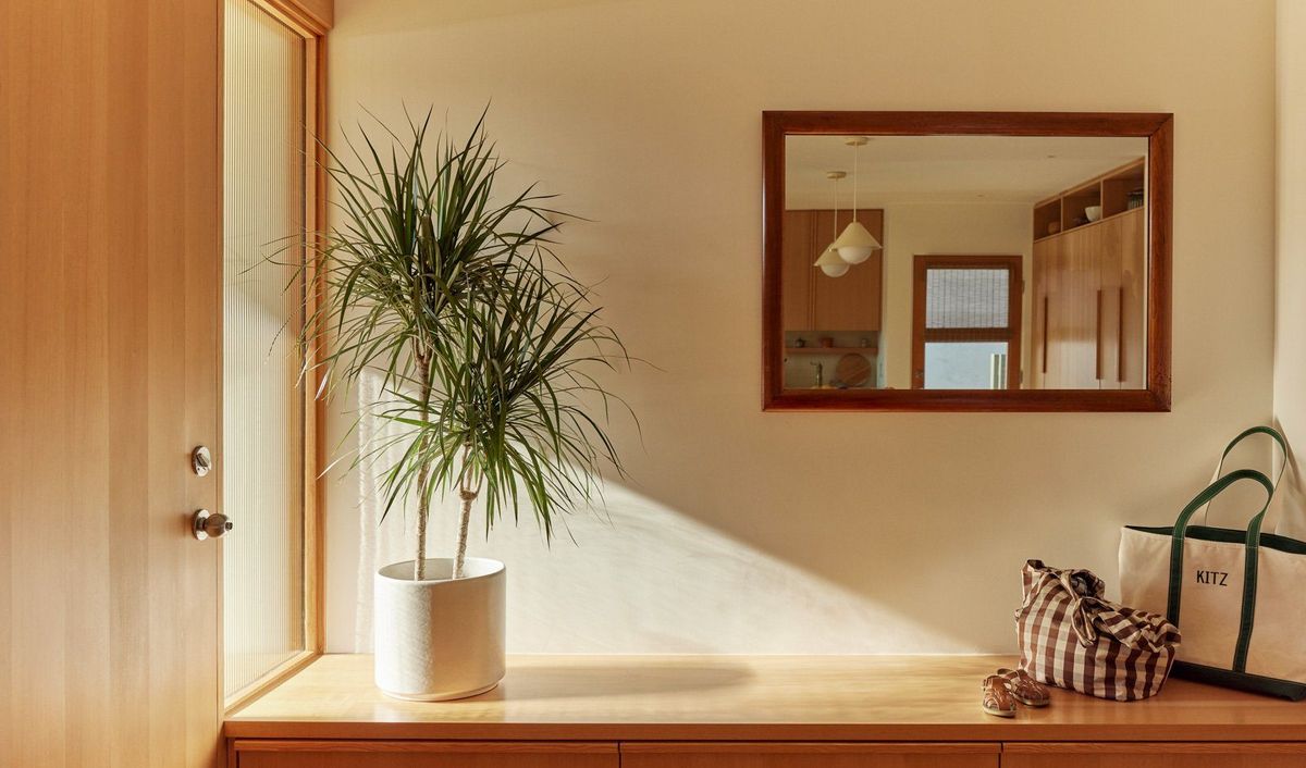Stewart: Entry nook with a wood mirror, bench and potted palm
