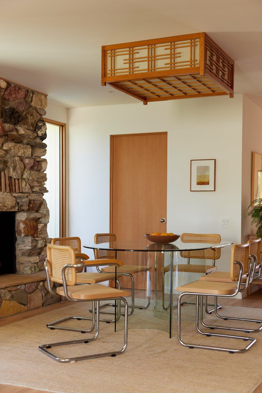 Stewart: Dining room with a glass table, cane chairs and stone fireplace