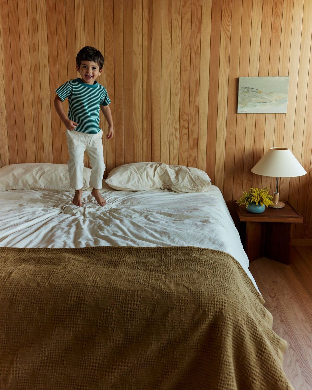 Stewart: Wood-paneled bedroom with a child standing on the bed