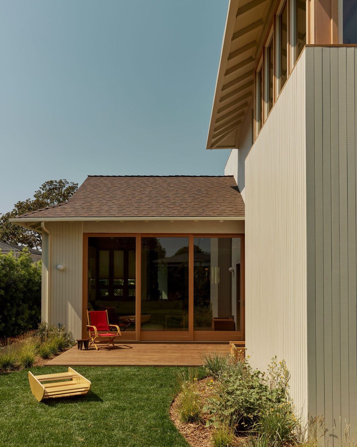 Stewart: Rear addition with wood-framed doors onto a lawn and sandbox